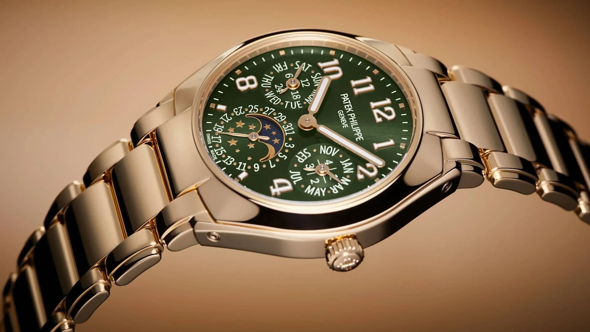 reloj dorado con esfera verde de calendario perpetuo, indicador de fase lunar y brazalete metálico visto en ángulo