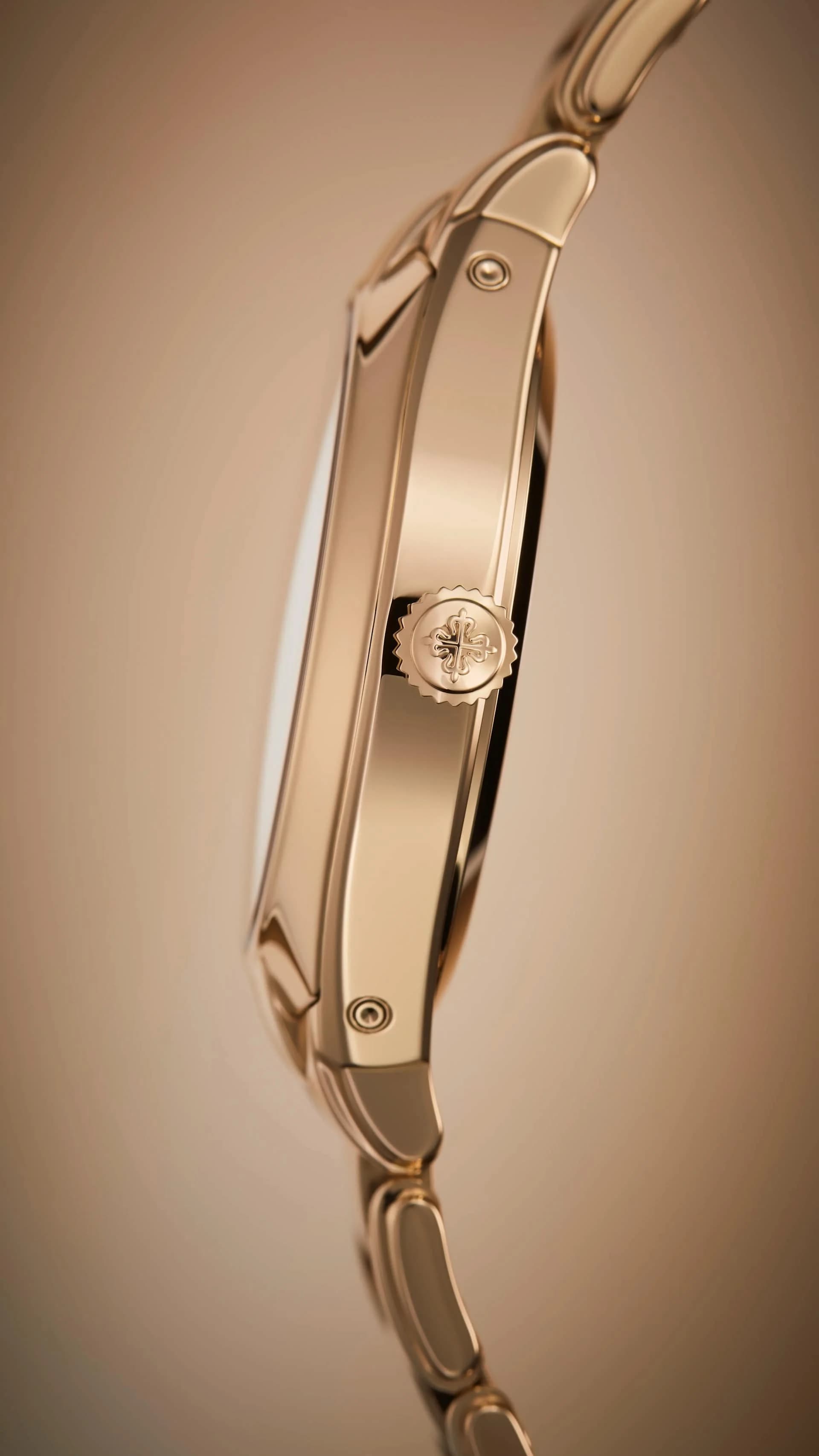 vista de perfil de un reloj dorado que muestra la corona con emblema grabado y el brazalete integrado