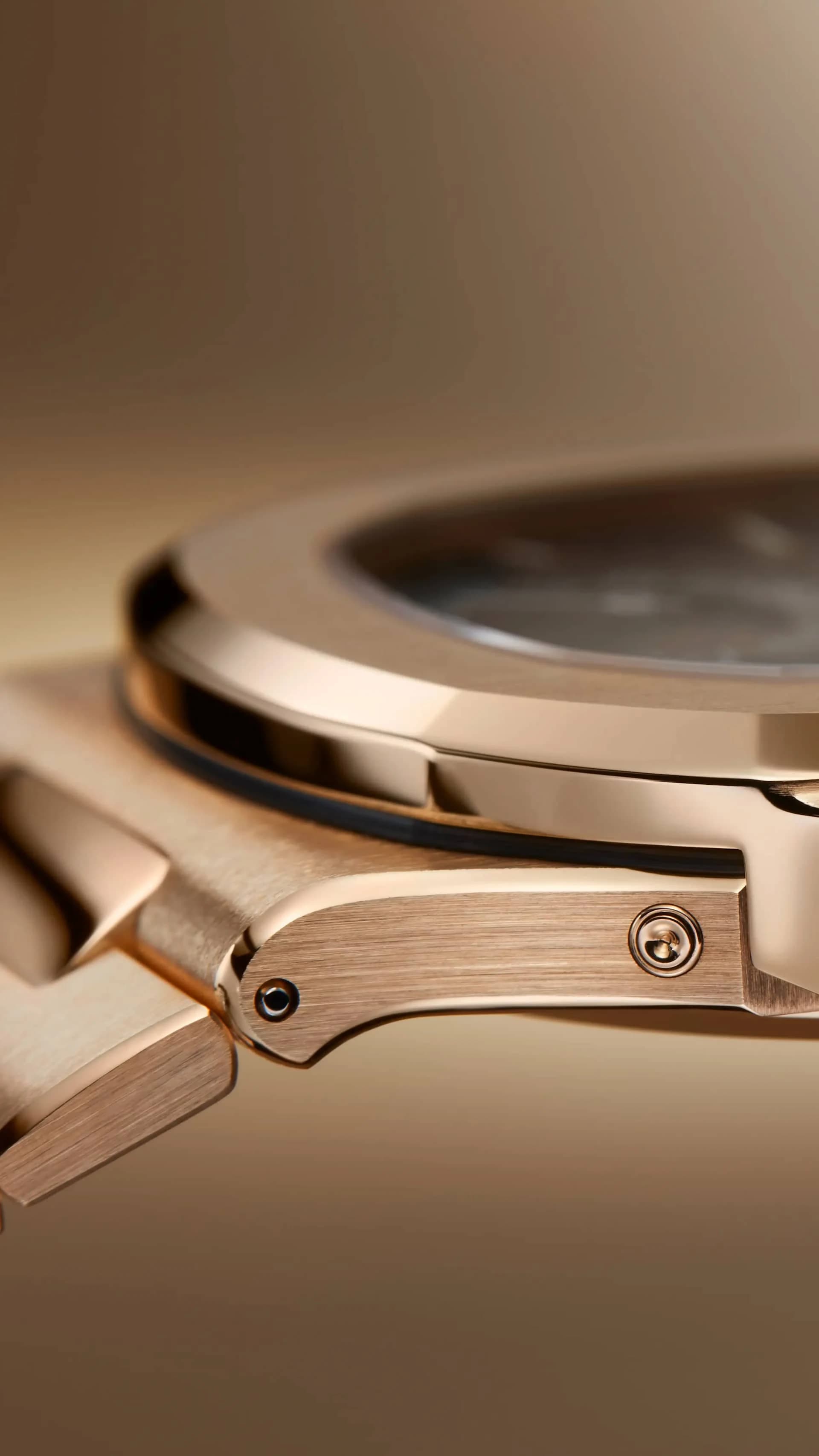 vista de perfil de un reloj de caja metálica en tono dorado rosado mostrando el eslabón articulado del brazalete con tornillo visible