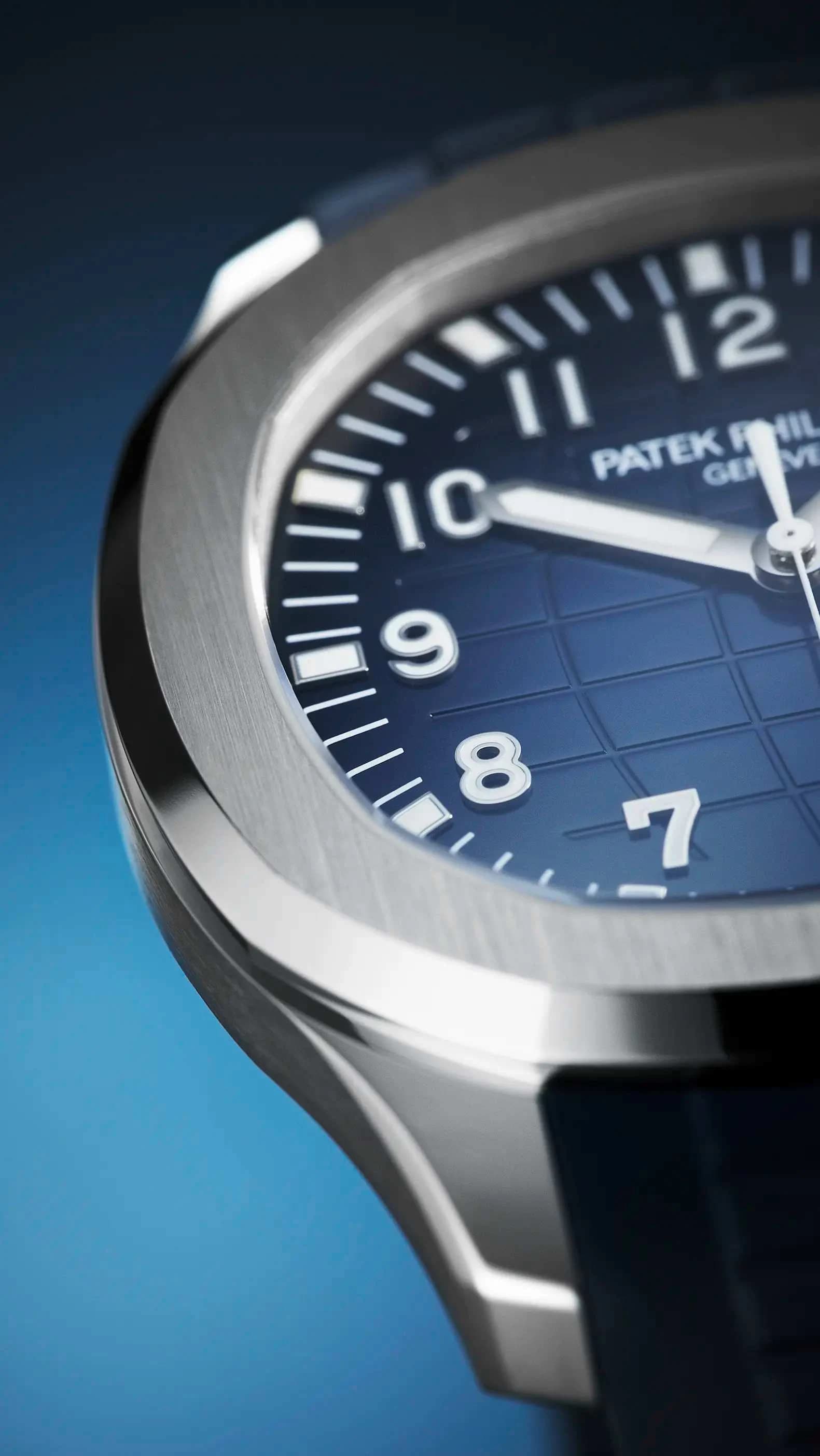 macro del bisel y la esfera azul con patrón de cuadros de un reloj Patek Philippe Geneve con caja metálica