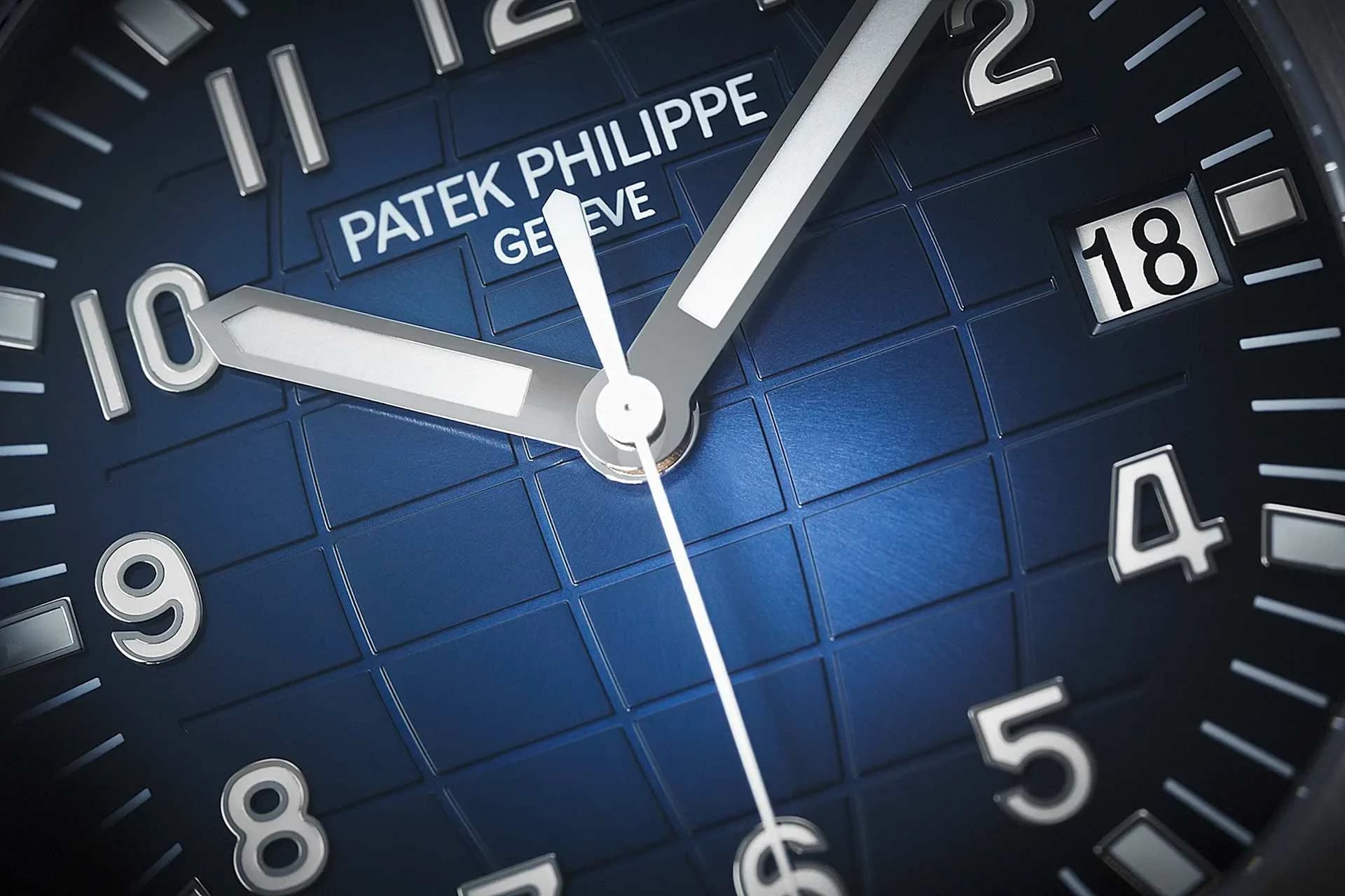 macro de la esfera azul con motivo de cuadrícula, agujas horaria y minutera, logotipo Patek Philippe Geneve y ventana de fecha marcando 18