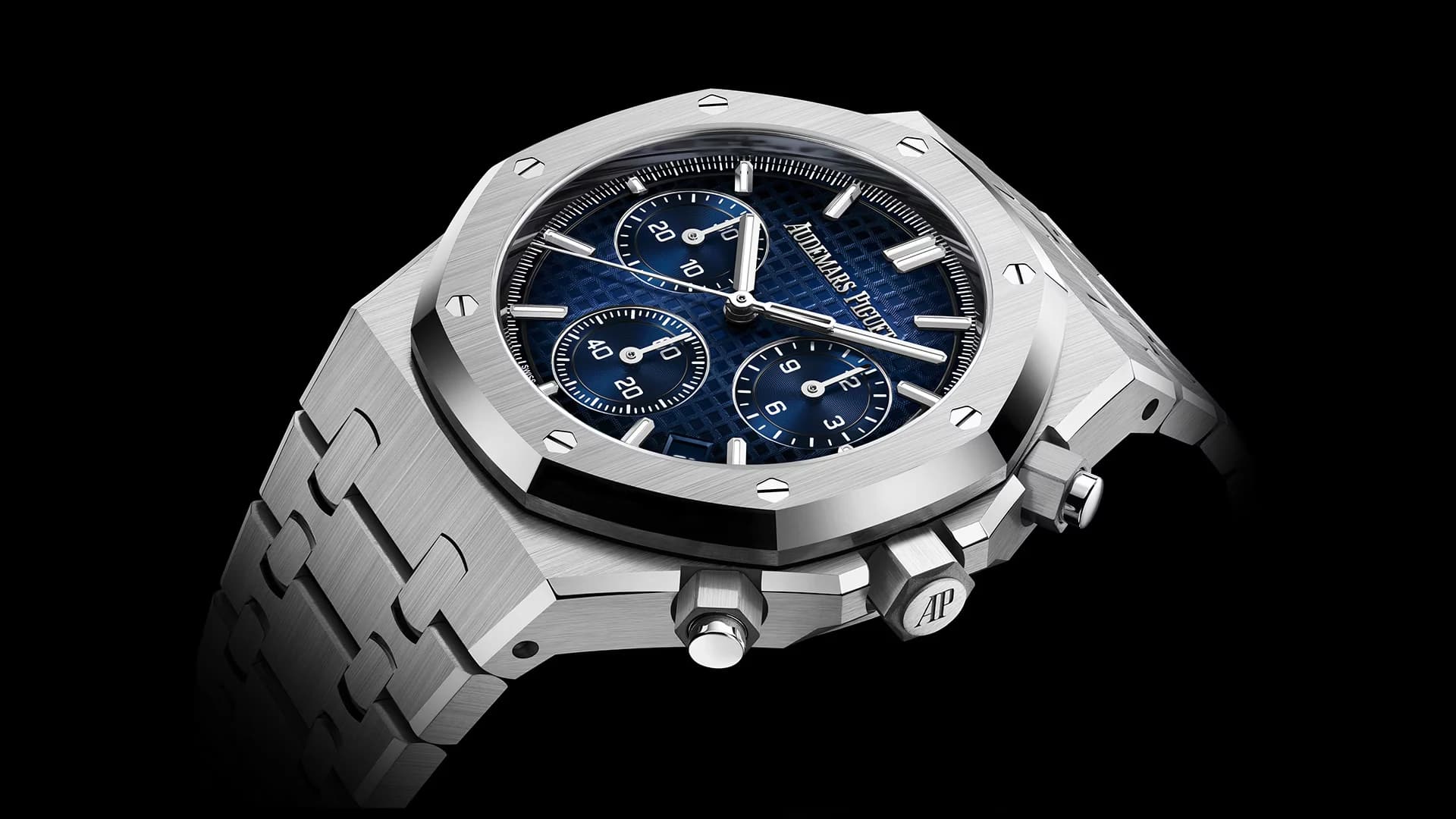 reloj de acero con esfera azul, bisel octogonal con tornillos visibles y tres contadores de cronógrafo