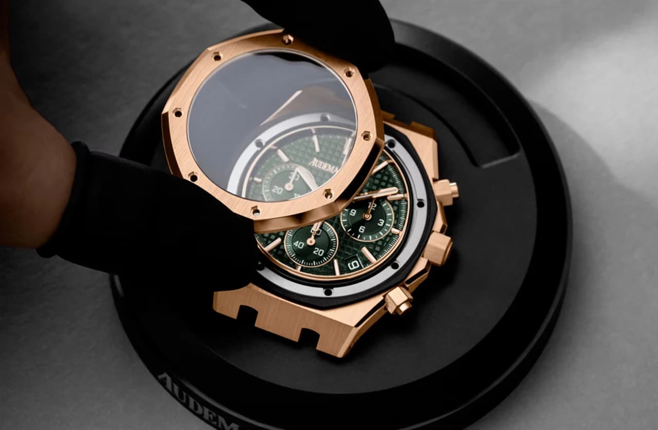 cronógrafo octagonal en oro rosa con esfera verde texturizada sostenido con guantes negros mientras se separa la caja del bisel