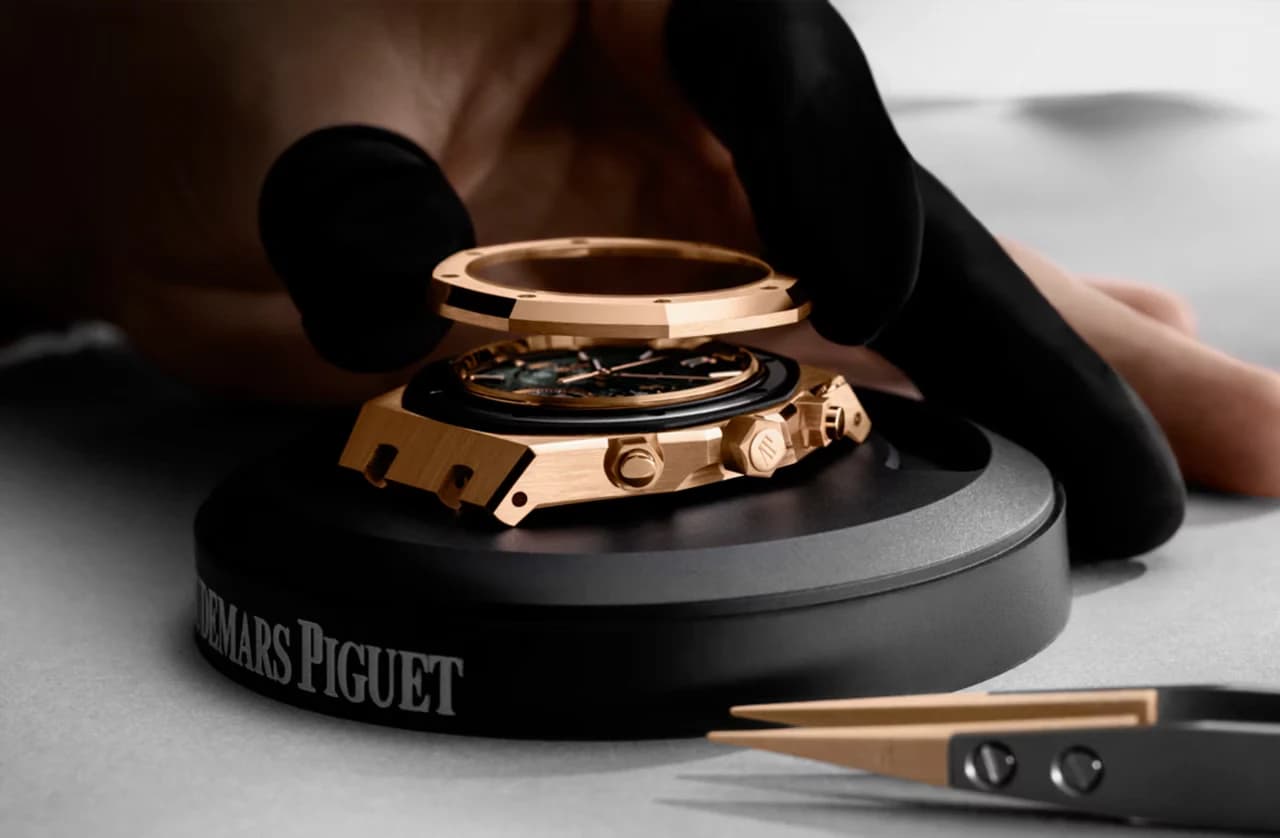 reloj de caja dorada con el bisel levantado durante su montaje sobre un soporte con el nombre Audemars Piguet