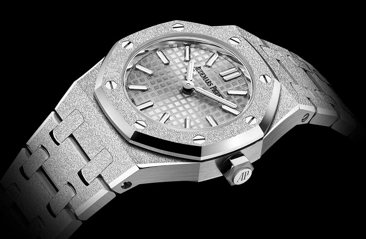 reloj con bisel octogonal de acabado martillado, esfera plateada con motivo de cuadrícula y corona a la derecha de la caja