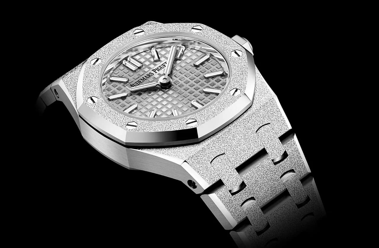 reloj con caja y brazalete de acabado escarchado, bisel octagonal con ocho tornillos visibles y esfera gris con patrón de motivo textil e índices aplicados