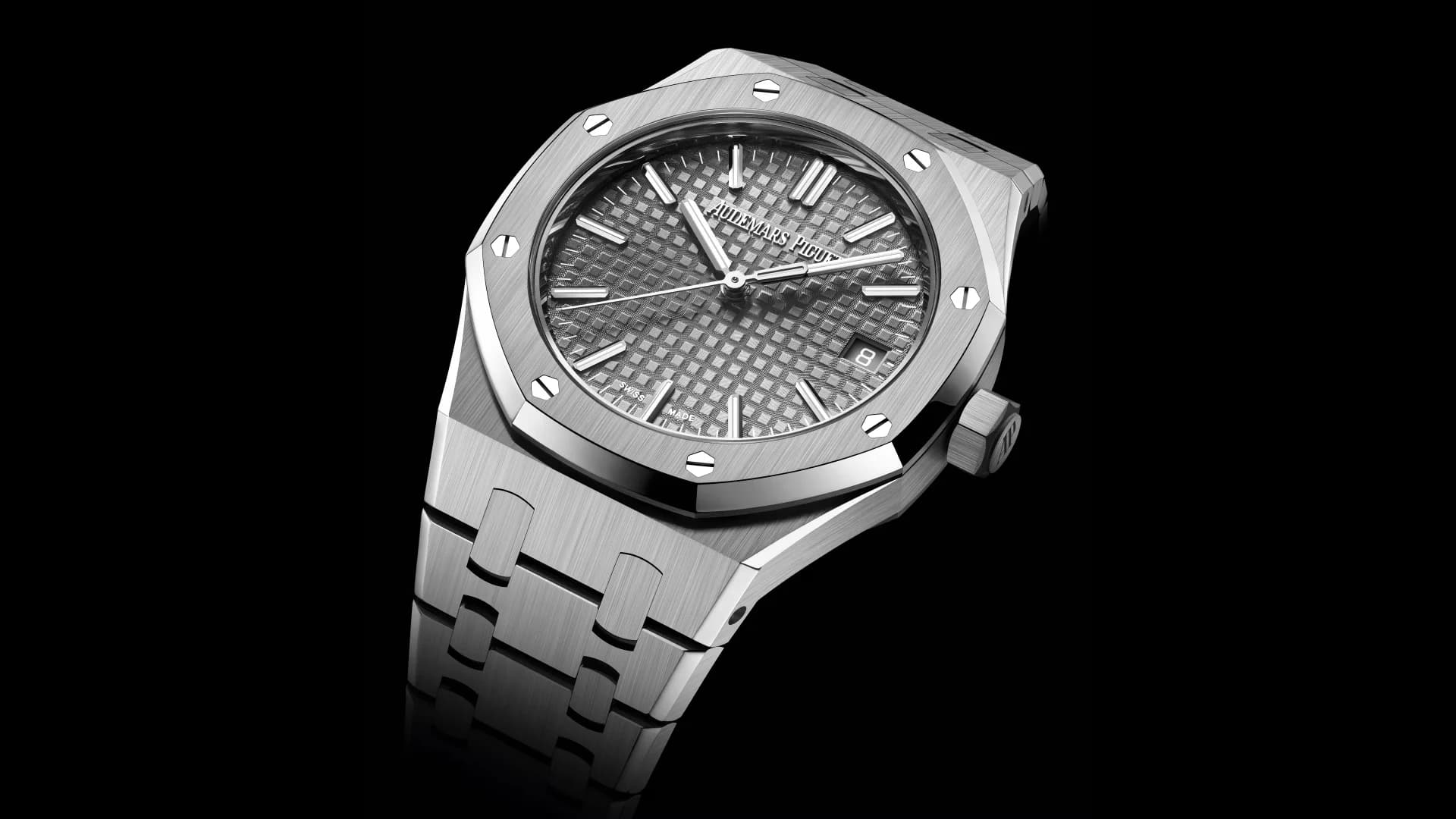 reloj de acero con bisel octogonal atornillado, esfera gris con motivo de cuadros y ventana de fecha a las tres, sobre fondo negro